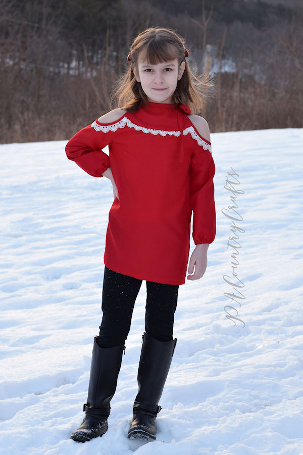 The cold shoulder Lynx dress with lace embellishment along the yoke and long sleeves with elastic wrist.