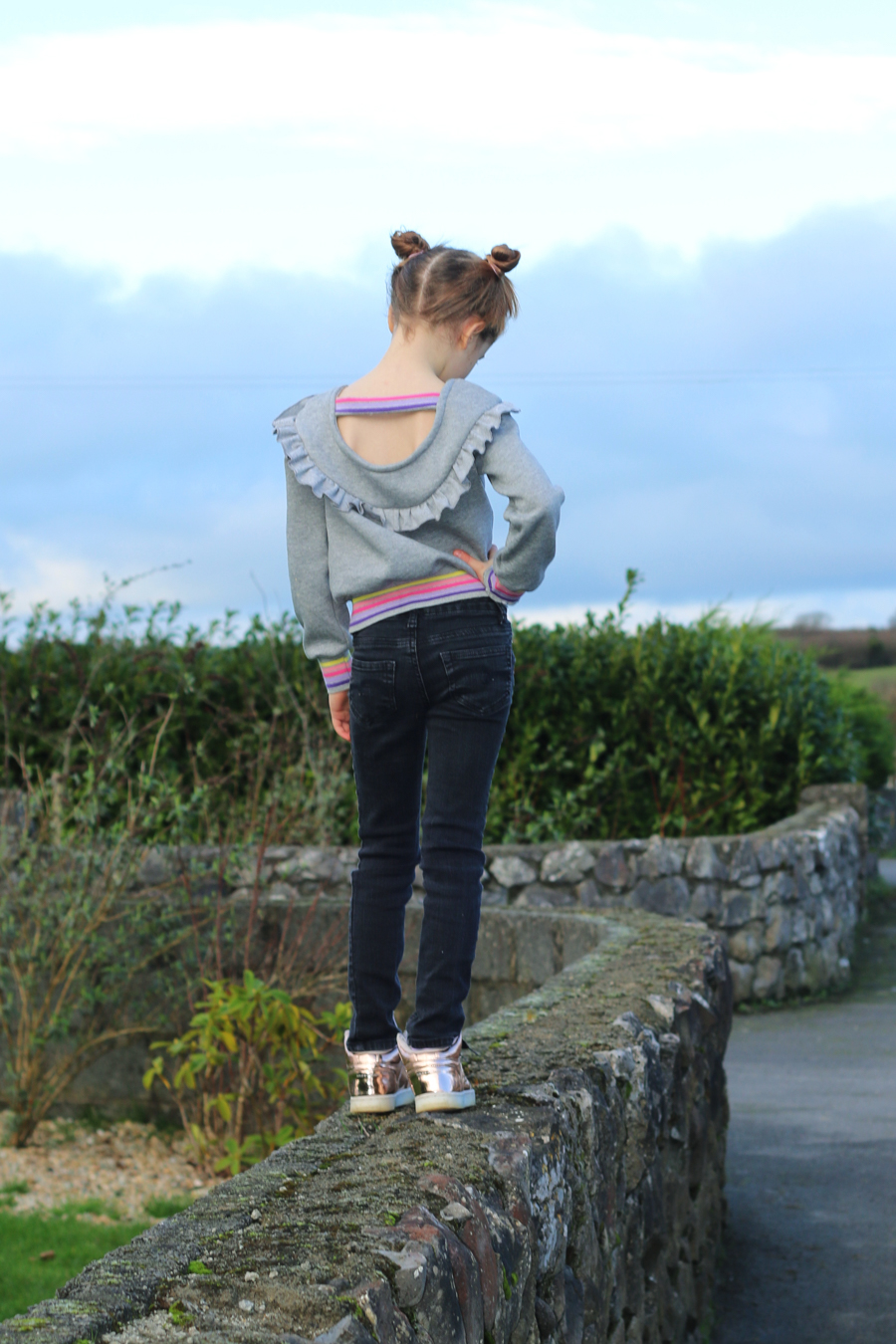 Rhubarb scoop back, dropped shoulder and shorter ruffled yoke with band across the back. Top length in knit fabric and striped cuff material. Perfect for tweens.