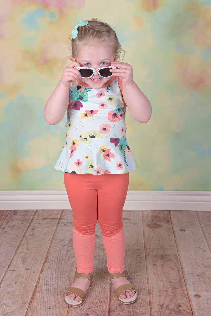 Dandelion Peplum tank with criss cross back and visible facings for an accent. Short peplum view. Shown with Rocky Shore tights.