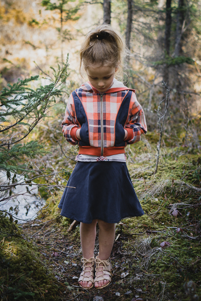 A plaid jacquard jersey Rose Hip jacket with hood and welt pockets and shown with the Spruce skirt.