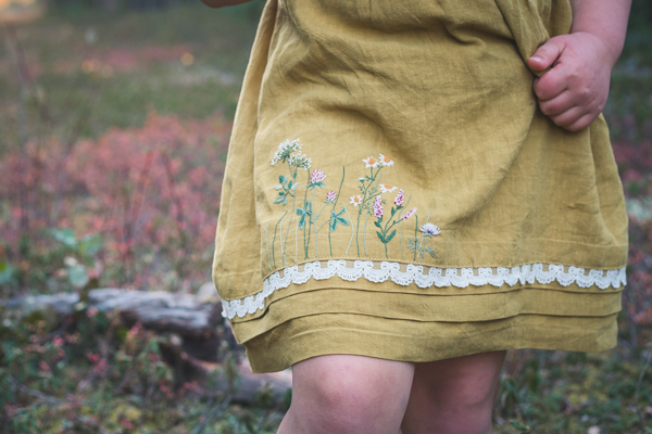 Hand embroidered flowers along the hem of a linen dress with deep pleats. Designed by Sofiona Designs.
